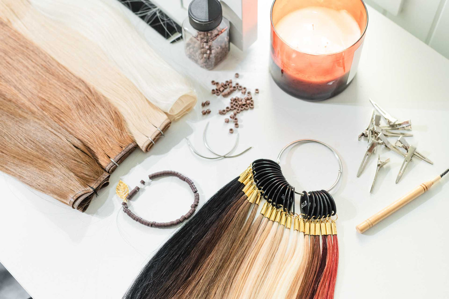 Hair extensions on a table with tools and a candle