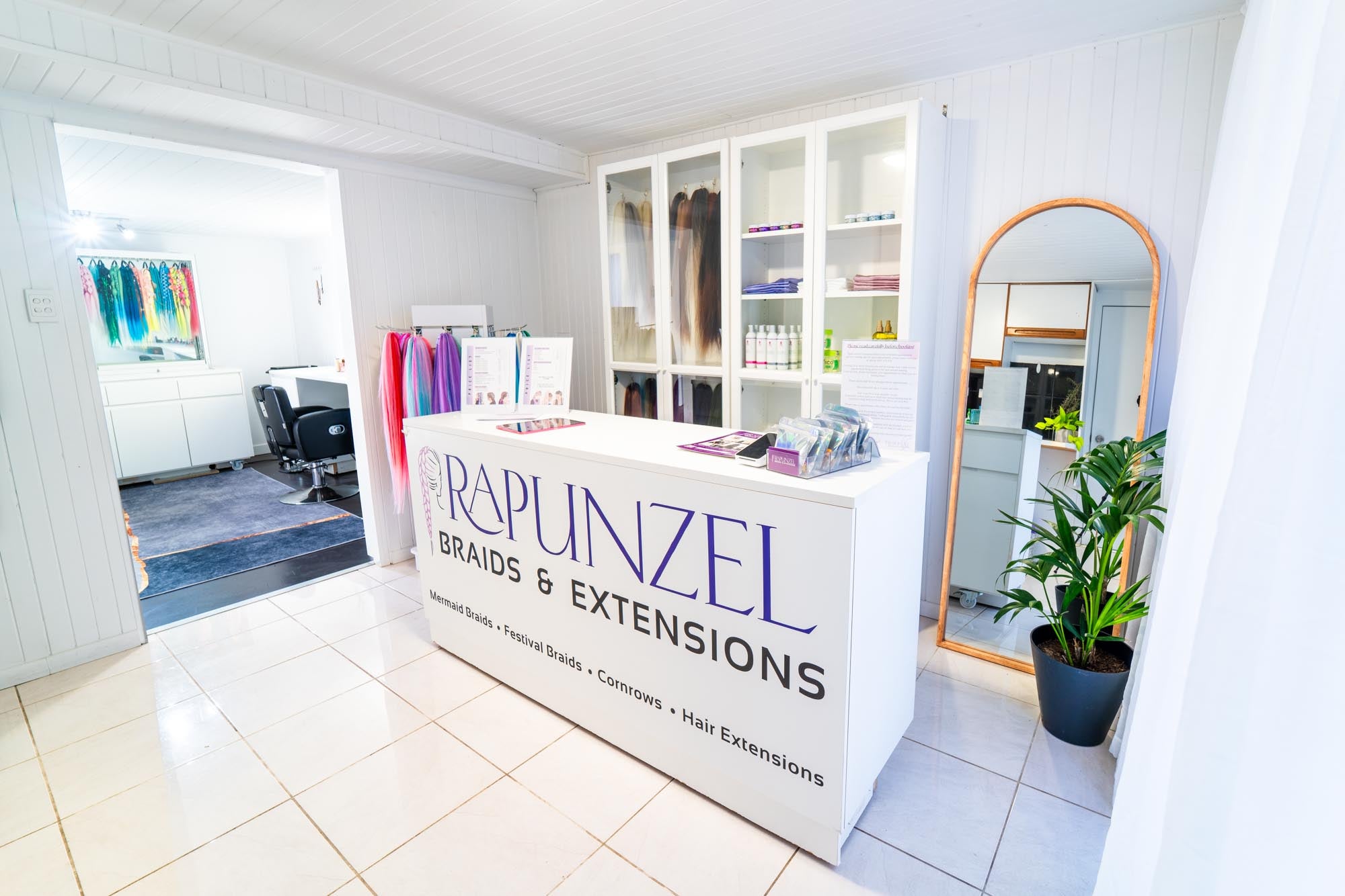 Hair extension store with 'Rapunzel Braids & Extensions' sign in a well-lit interior.